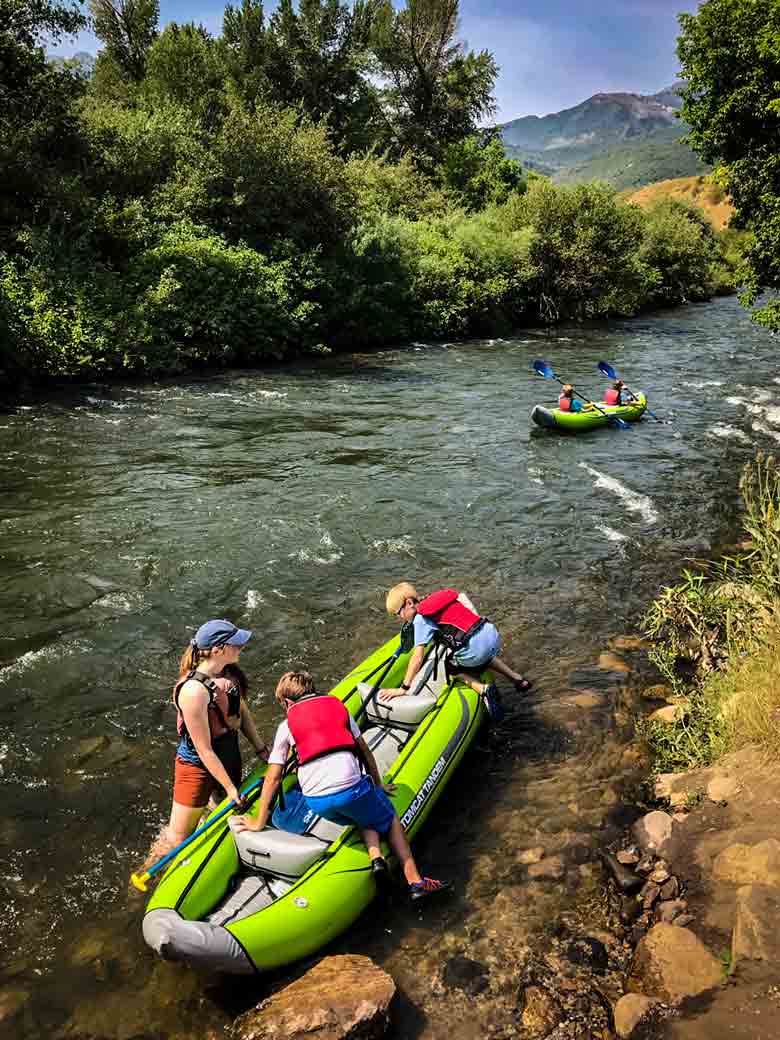 A guide helps boys into a kayak during a Provo River kayak trip in Utah.