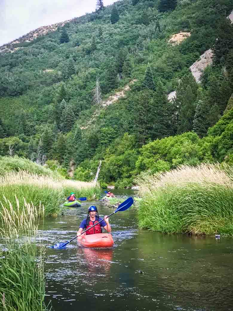 Three people kayaking on the Provo River near Orem and Park City Utah.