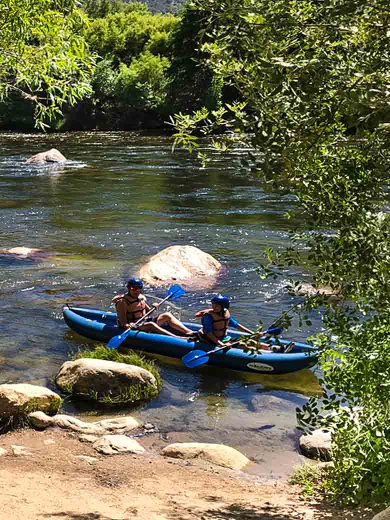Two people about to start a whitewater kayak river trip on the Kern River in the Sequoia National Forest in California.