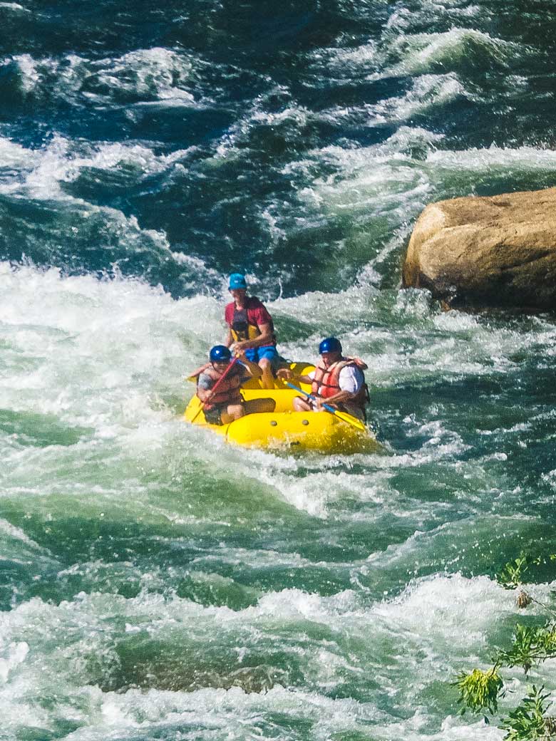Men whitewater rafting in a yellow raft on the Kern River in Kernville California.