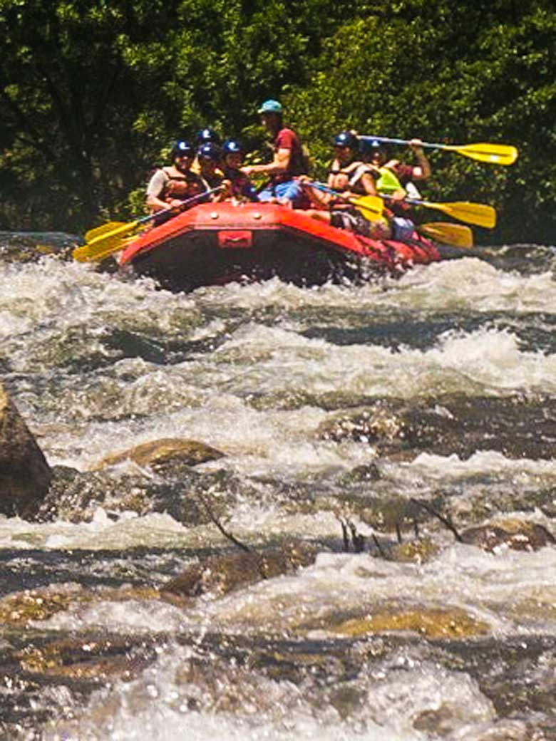Men whitewater rafting in a red raft on the Kern River in Kernville California.