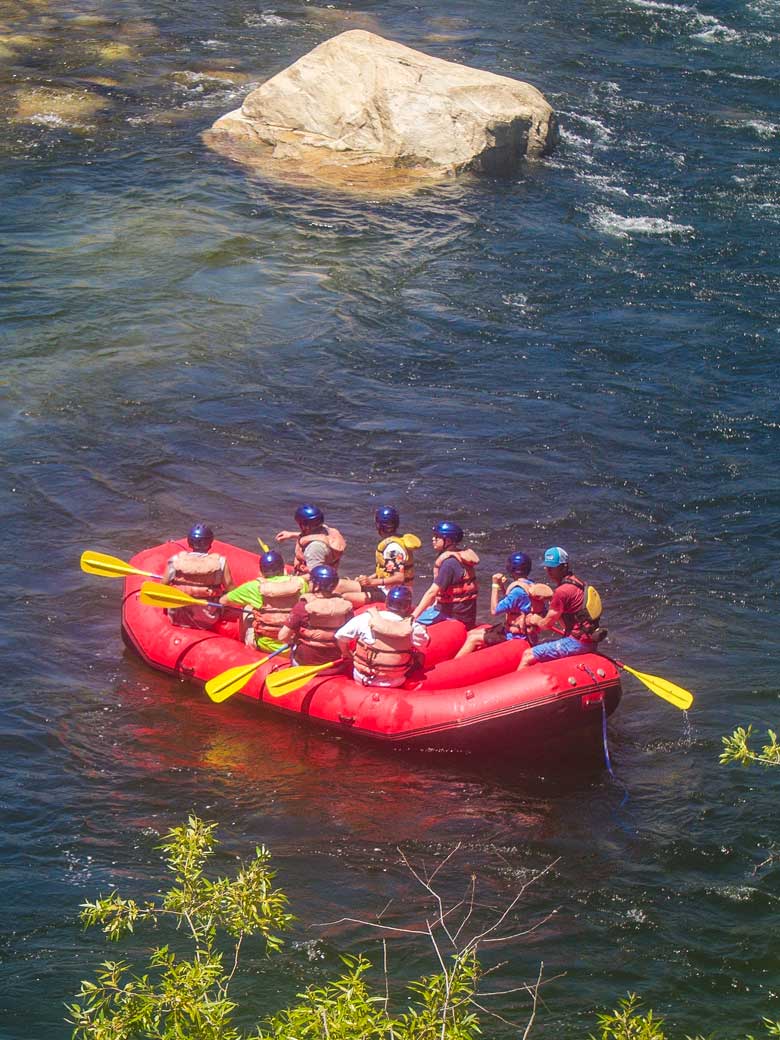 Men whitewater rafting in a red raft on the Kern River in Kernville California.