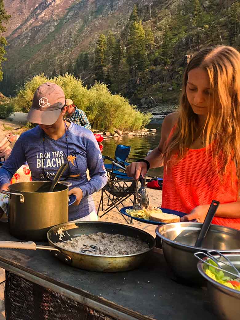Two girls serving dinner during a Main Salmon River whitewater rafting vacation in Idaho.