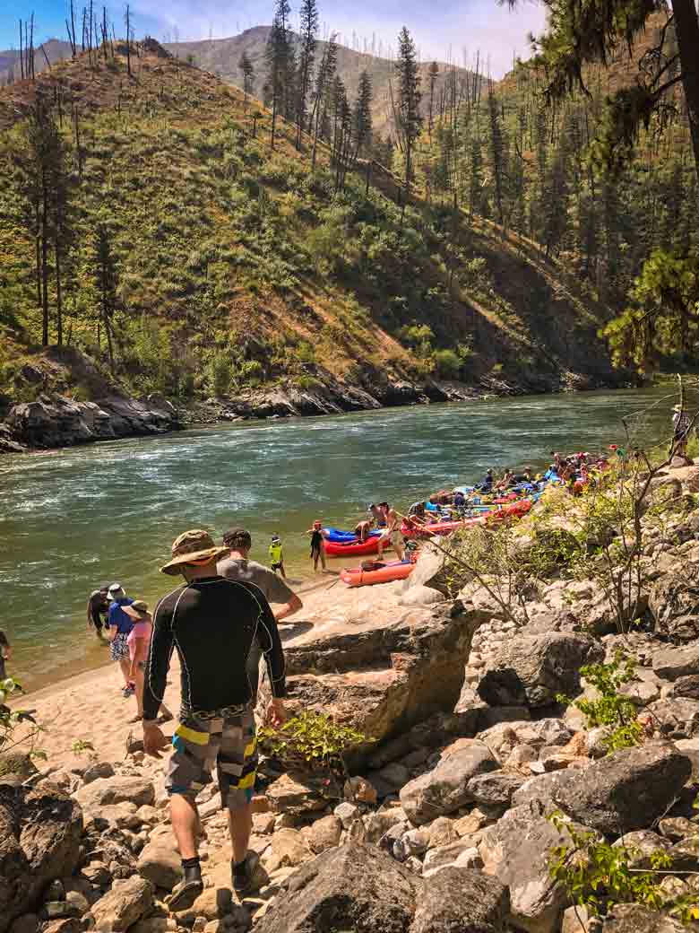 A group hiking to rafts and kayaks along the river during a Main Salmon River whitewater rafting vacation in Idaho.
