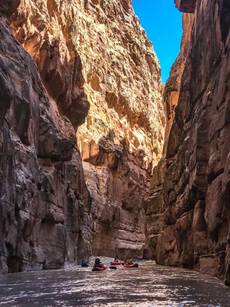 Four people kayaking and river rafting in a canyon near Canyonlands National Park and Moab Utah.