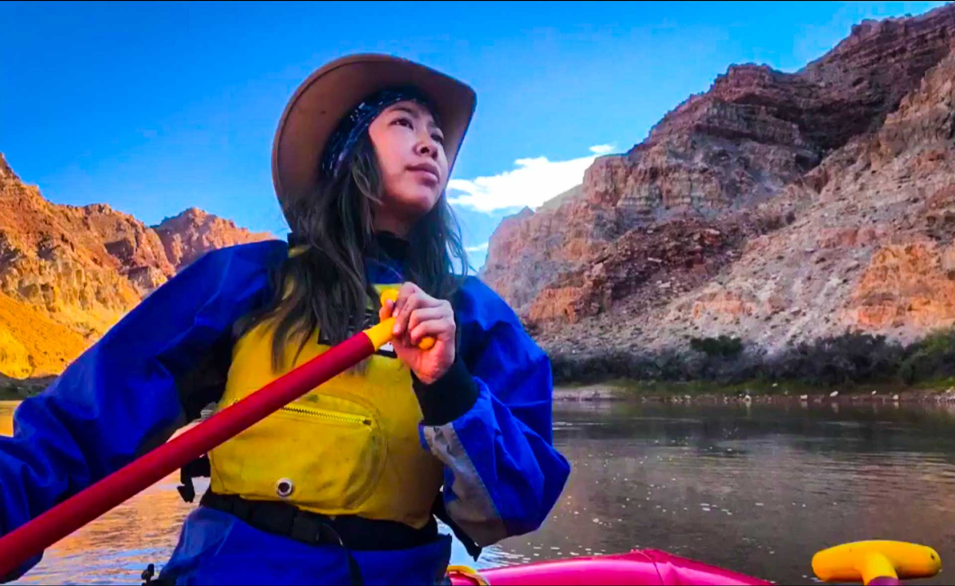 Girl paddling while seated in a whitewater raft on the Colorado River in Cataract Canyon in Canyonlands National Park near Moab Utah.