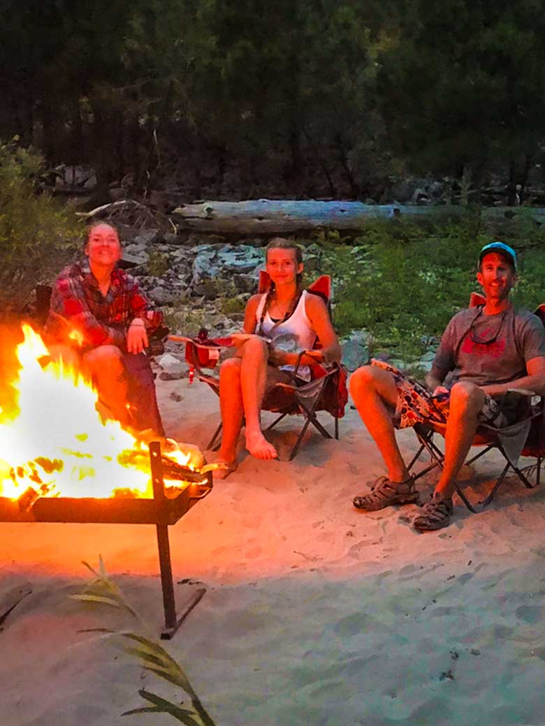 Three people enjoying a campfire during a whitewater rafting trip on the Main Salmon River in Idaho.